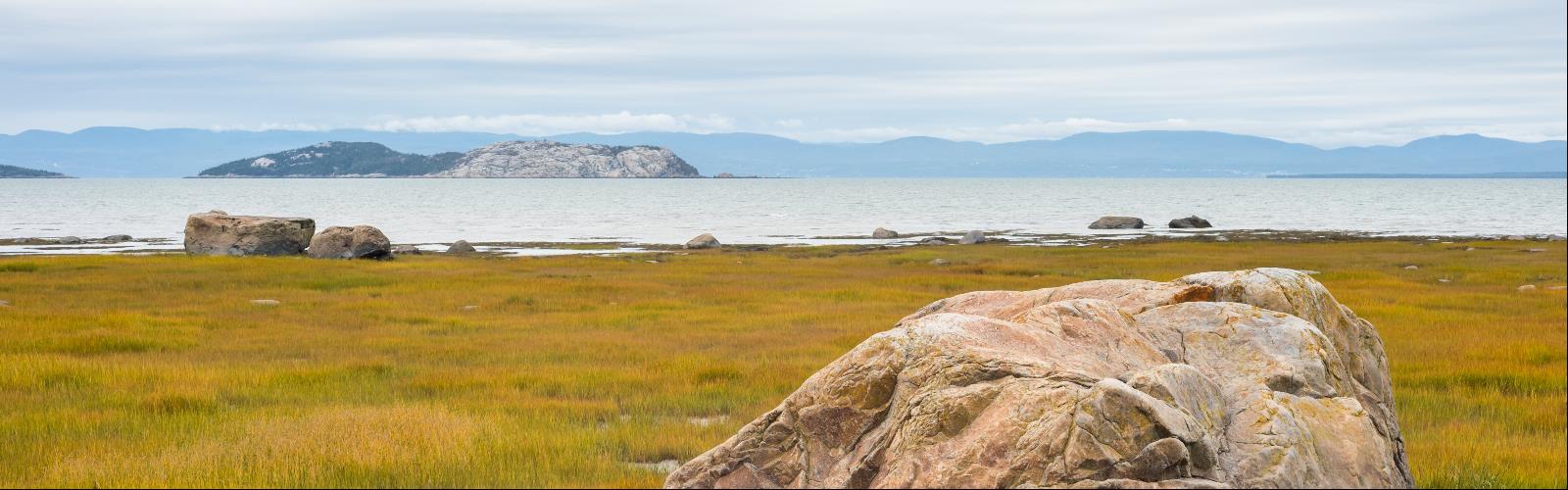 grass sky outdoor beach mountain lake water nature cloud landscape field rock grassy promontory overlooking lush distance