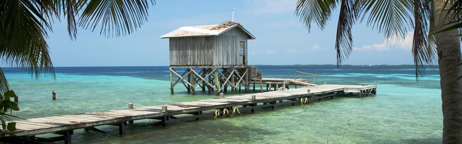 sky outdoor water beach lake wooden chair pier palm shore dock ocean overlooking lined resort several